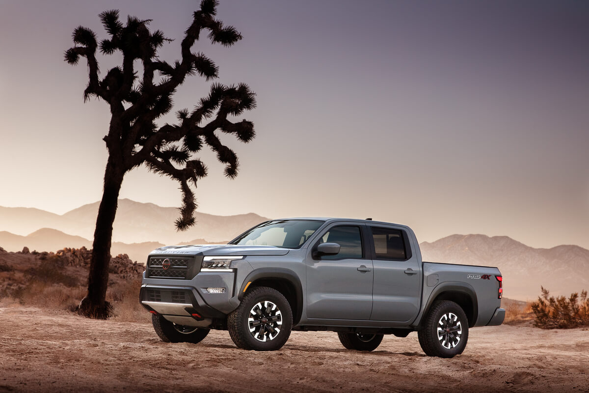 Vue 3/4 latérale du Nissan Frontier 2022 de couleur gris rocher nacré garé dans un désert