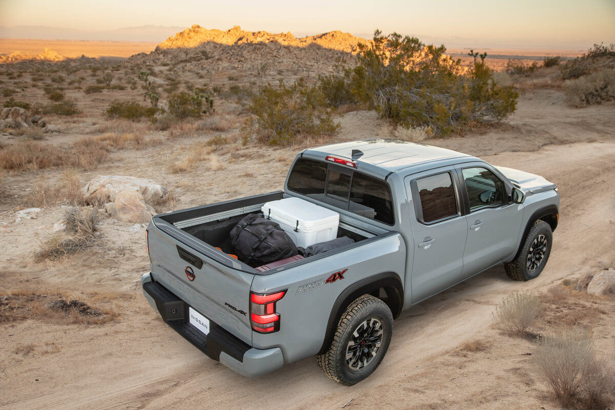 Vue 3/4 arrière du Nissan Frontier 2022 gris rocher nacré transportant des bagages dans sa caisse