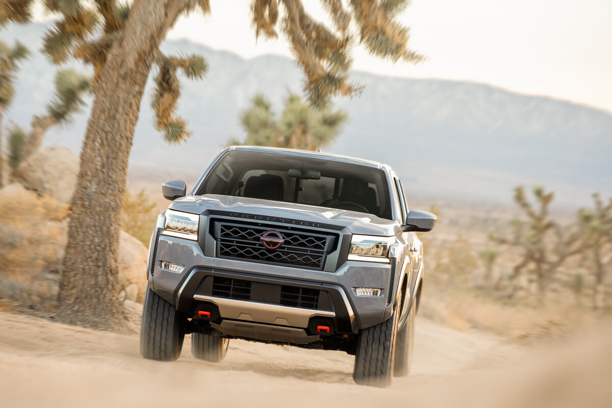 Vue avant du Nissan Frontier 2022 gris rocher nacré roulant sur une route dans un désert