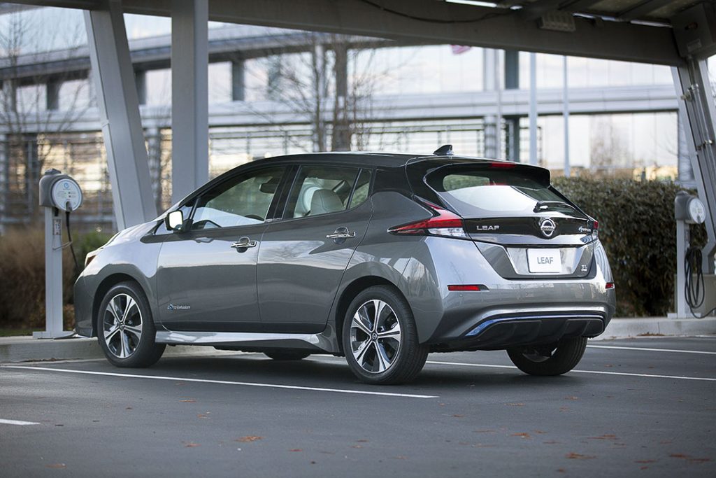 Nissan Leaf 2022 gris poudre métallisé vu de côté et de dos, à une borne de chargement